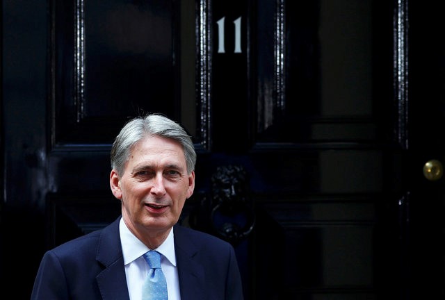 © Reuters. Britain's new Chancellor of the Exchequer, Philip Hammond, waits to greet U.S. Treasury Secretary Jack Lew, at number 11 Downing Street in London