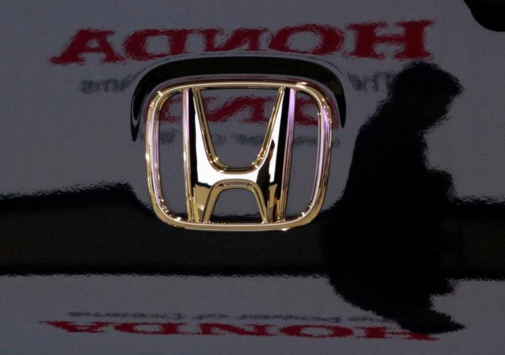 © Reuters. Visitor and logo of Honda Motor Co are reflected on a Honda car at company headquarters in Tokyo