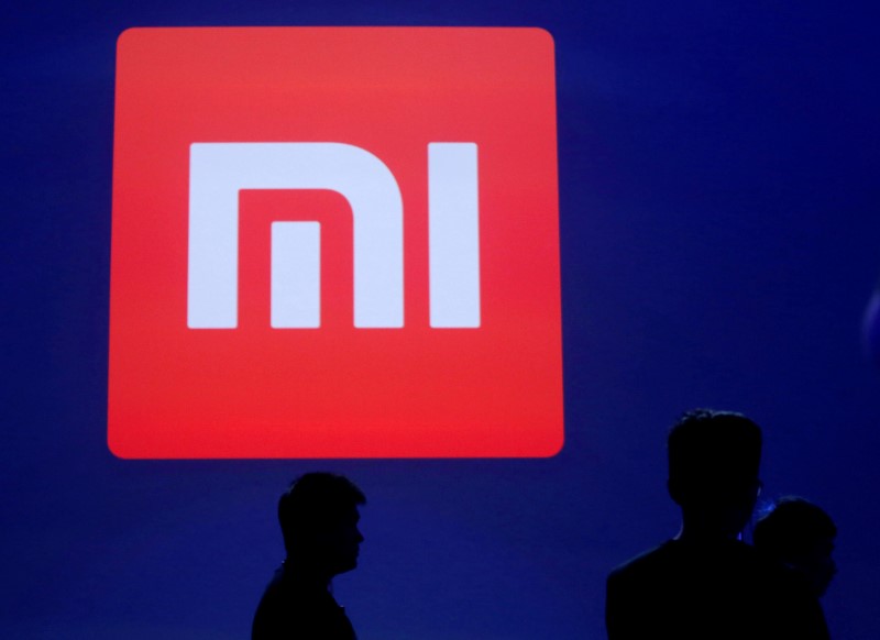 © Reuters. Attendants are silhouetted in front of Xiaomi's logo in Beijing