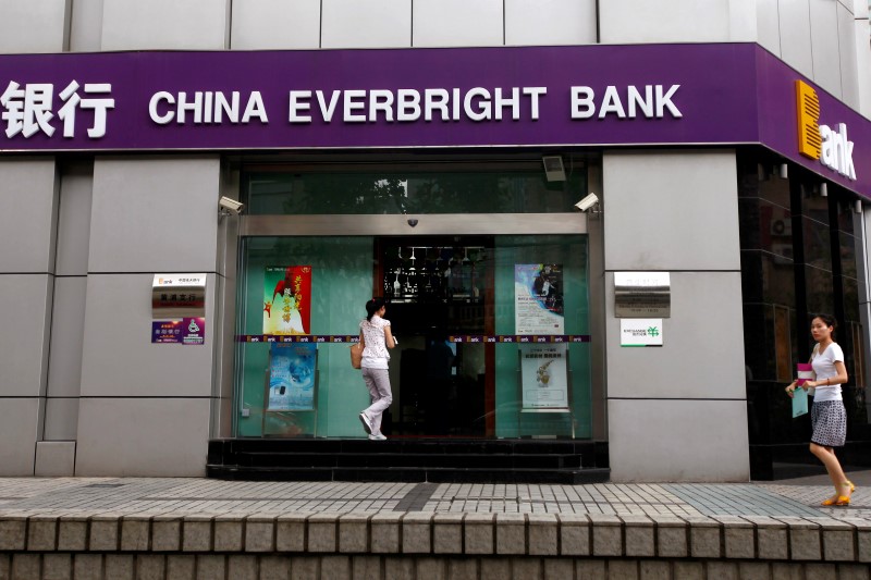 © Reuters. Passers-by walk past a branch of China Everbright Bank in Shanghai