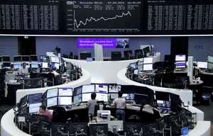 © Reuters. Traders work at their desks in front of the German share price index, DAX board, at the stock exchange in Frankfurt