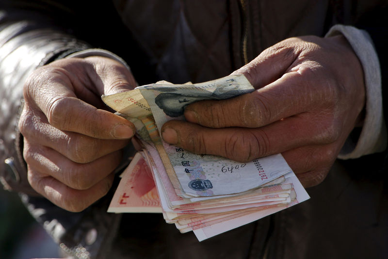 © Reuters. A vegetable vendor counts his money at a market in Beijing