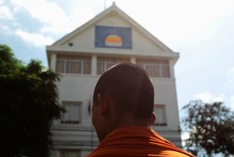 © Reuters. A Buddhist monk stands in front of the Cambodia National Rescue Party headquarters as he listens to a speech of leader Kem Sokha, in Phnom Penh,