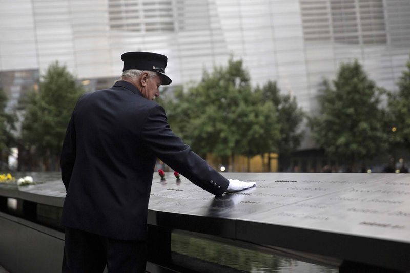 © Reuters. A member of the New York Fire Department places his hand on the memorial before a ceremony marking the 14th anniversary of the 9/11 attacks, at the National September 11 Memorial and Museum in Lower Manhattan in New York