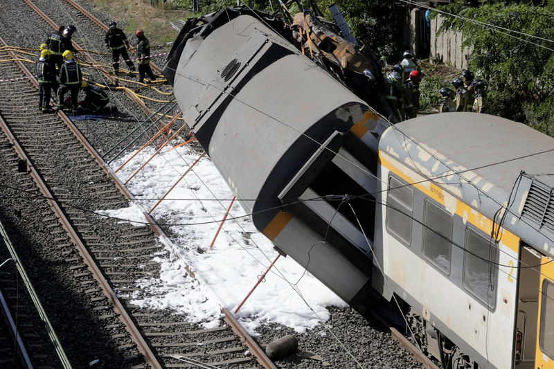 © Reuters. Firefighters work at the scene of a train that derailed in Galicia in north-western Spain