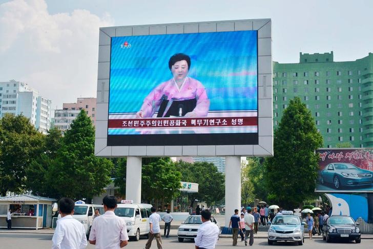 © Reuters. Norte-coreanos , em Pyongyang, caminham perto de uma tela gigante durante transmissão do anúncio do governo de que a Coreia do Norte realizou o seu quinto teste nuclear