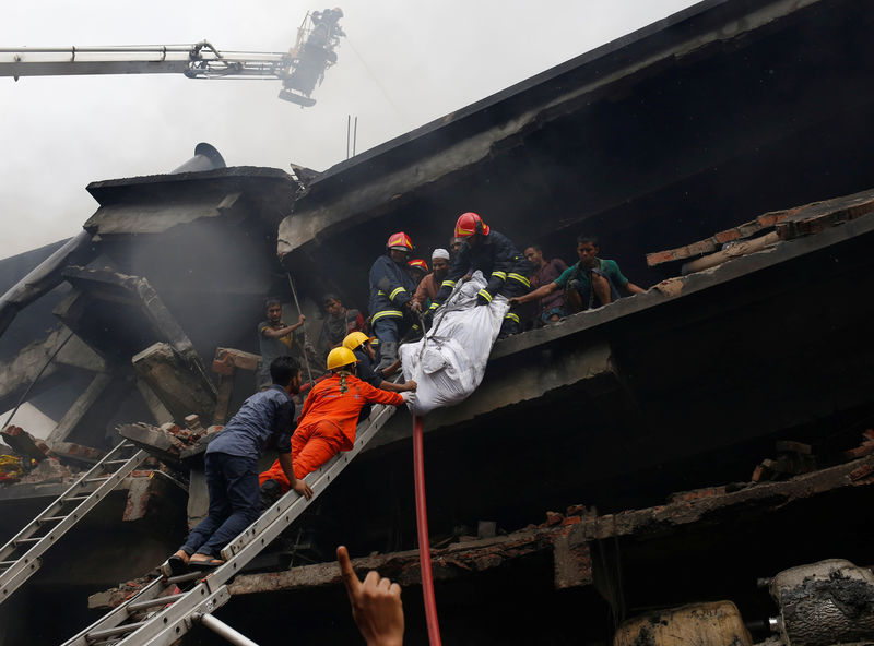 © Reuters. Firefighters remove a dead body at a food and cigarette packaging factory after fire broke out outside of Dhaka Dhaka