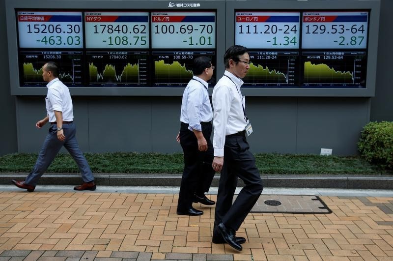 © Reuters. Passersby walk past in front of electronic boards showing Japan's Nikkei share average, the Japanese yen's exchange rate against the U.S. dollar, British pound and Euro outside a brokerage in Tokyo, Japan