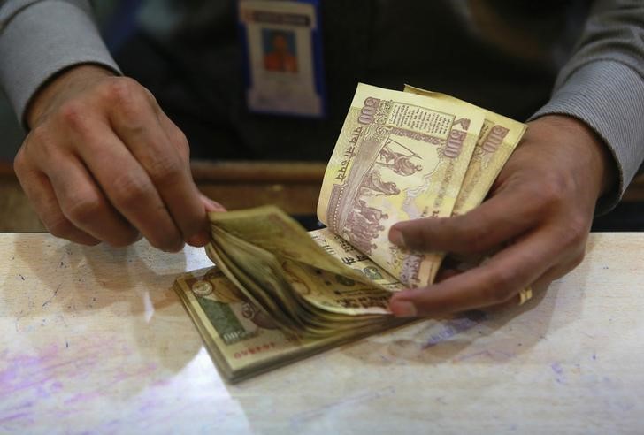 © Reuters. A cashier counts Indian rupee currency notes inside a bank in Mumbai
