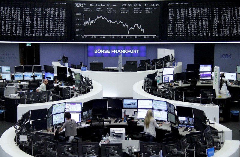 © Reuters. Traders work at their desks in front of the German share price index, DAX board, at the stock exchange in Frankfurt