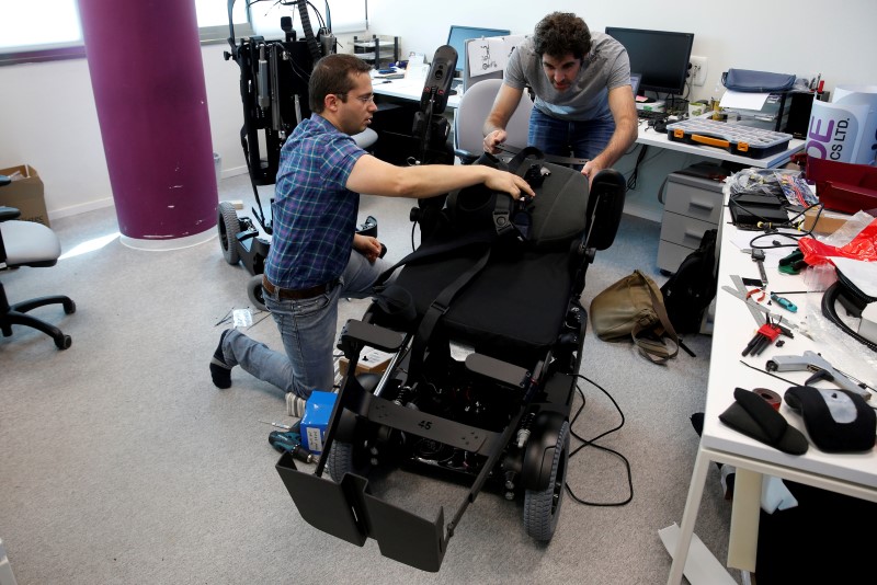 © Reuters. Employees work on a wheelchair developed by Israeli company UPnRIDE Robotics, that enables paralysed people with limited function in their arms to stand upright, during a demonstration at their offices in Yoqneam