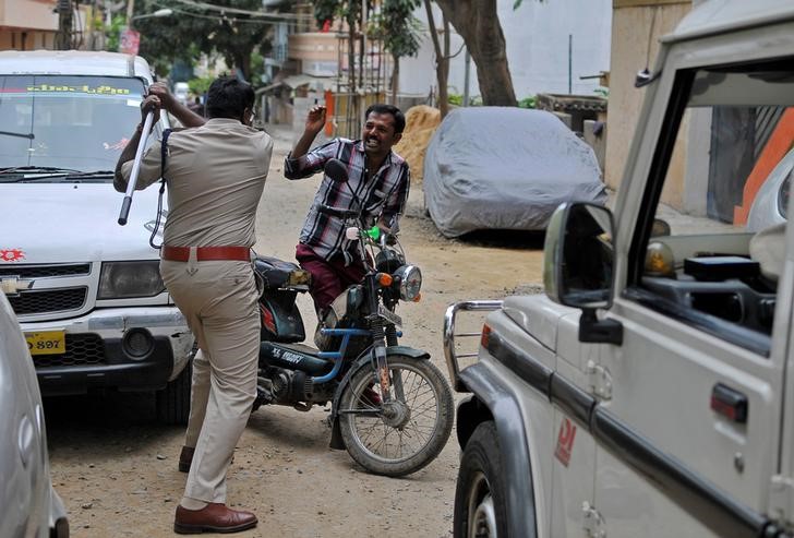 © Reuters. Policial levantando bastão contra homem em Bangalore