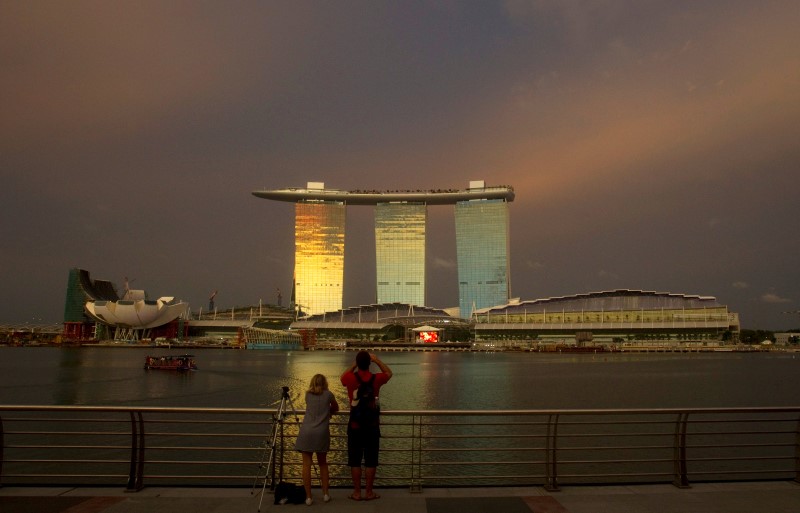 © Reuters. Tourists stand at a promenade across the water from the Marina Bay Sands integrated resort in Singapore