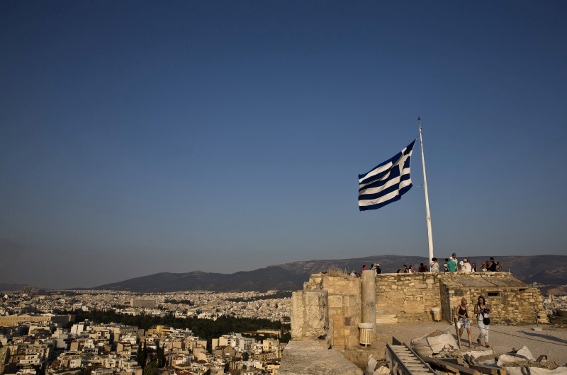© Reuters. Greek flag flutters in the wind as tourists visit the archaeological site of the Acropolis hill in Athens, Greece