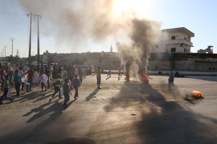 © Reuters. People gather near burning tyres during a demonstration against forces loyal to Syria's President Bashar al-Assad and calling for aid to reach Aleppo near Castello road in Aleppo