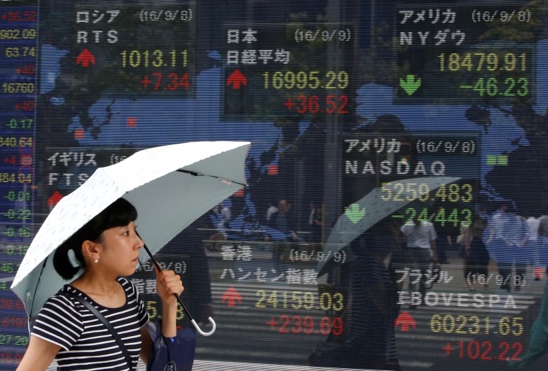 © Reuters. A woman walks past stock quotation board outside a brokerage in Tokyo