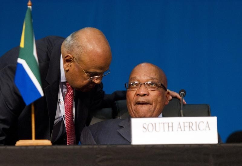 © Reuters. South Africa's Finance Minister Pravin Gordhan speaks to President Jacob Zuma during closing remarks during the 5th BRICS Summit in Durban