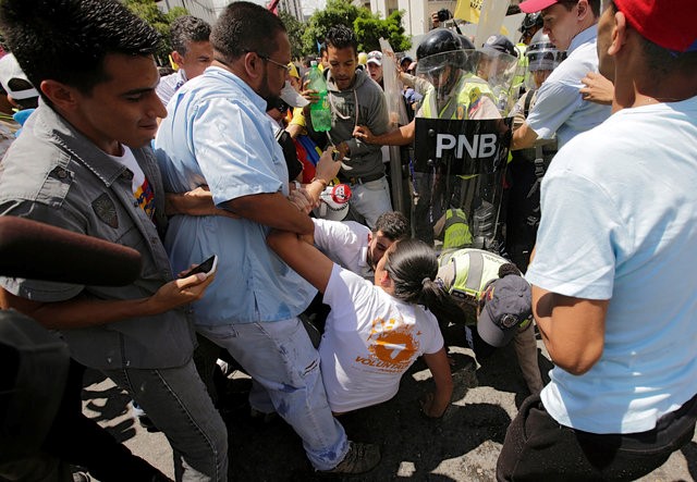 © Reuters. Supporters of Venezuela's opposition face police officers who are blocking a street, as they take part in a rally to demand a referendum to remove Venezuela's President Nicolas Maduro, in Caracas