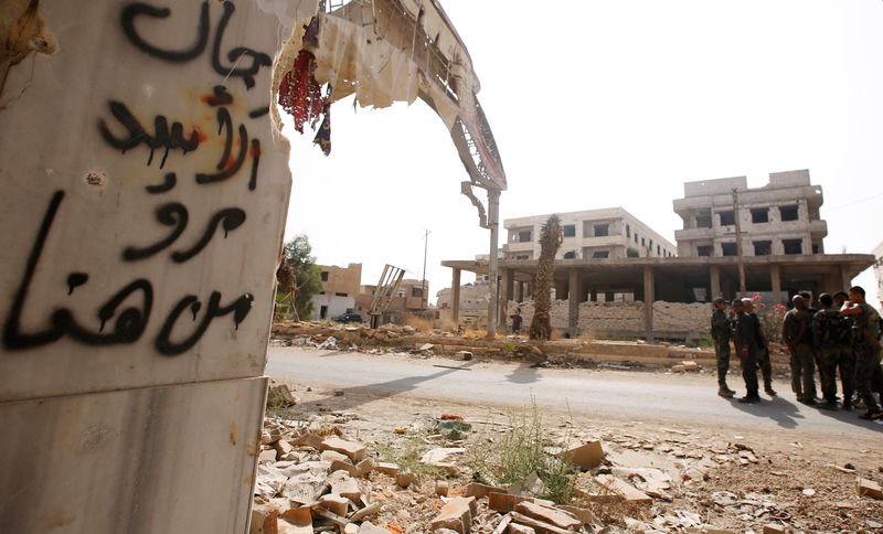 © Reuters. A Syrian army soldier stands at the entrance of the besieged Damascus suburb of Daraya, before the start of evacuation of residents and insurgents of Daraya