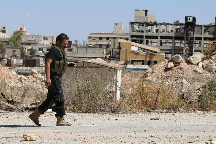 © Reuters. A rebel fighter walks by damaged buildings near Castello road in Aleppo