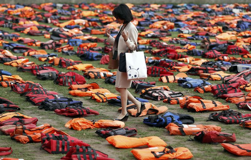 © Reuters. A woman walks through a display of lifejackets worn by refugees during their crossing from Turkey to the Greek island of Chois, in Parliament Square in central Londo