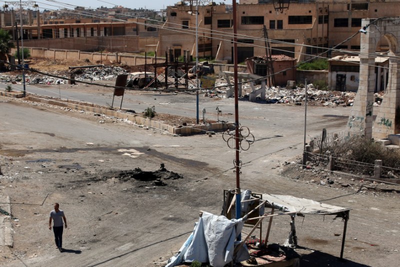 © Reuters. A man walks near a hole in the ground after an airstrike on Sunday in the rebel-held town of Dael