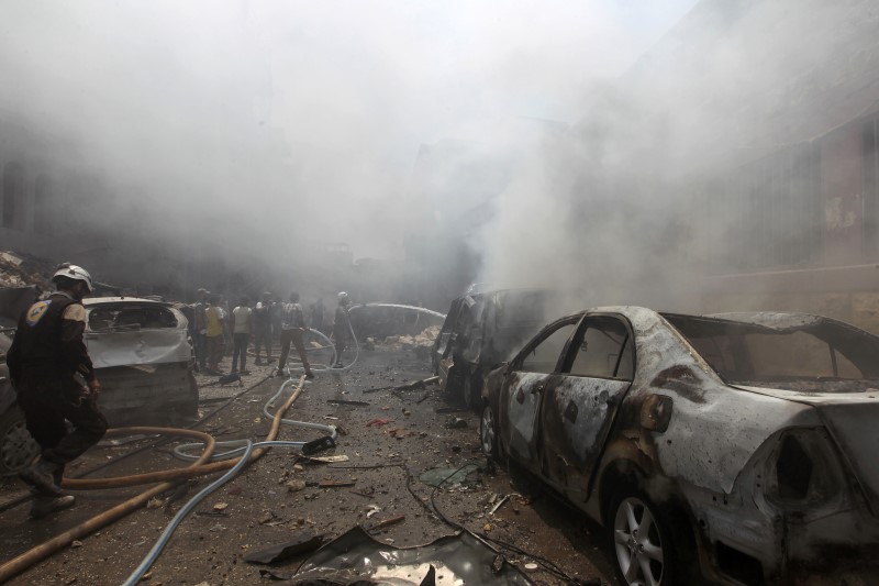 © Reuters. Smoke rises over a damaged site as Civil Defence members try to put out a fire after an airstrike on al-Jalaa street in the rebel held city of Idlib