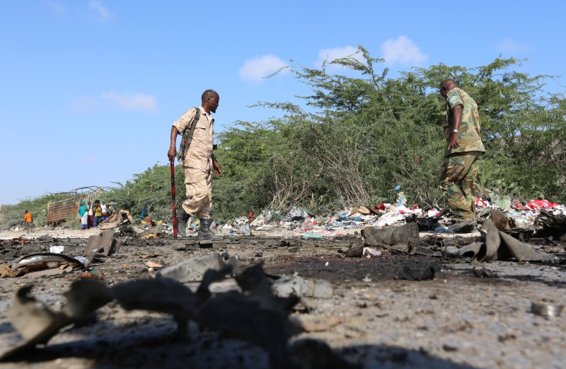 © Reuters. Somali soldiers inspect the scene of a suicide car bomb attack by al Shabaab in Somalia's capital Mogadishu