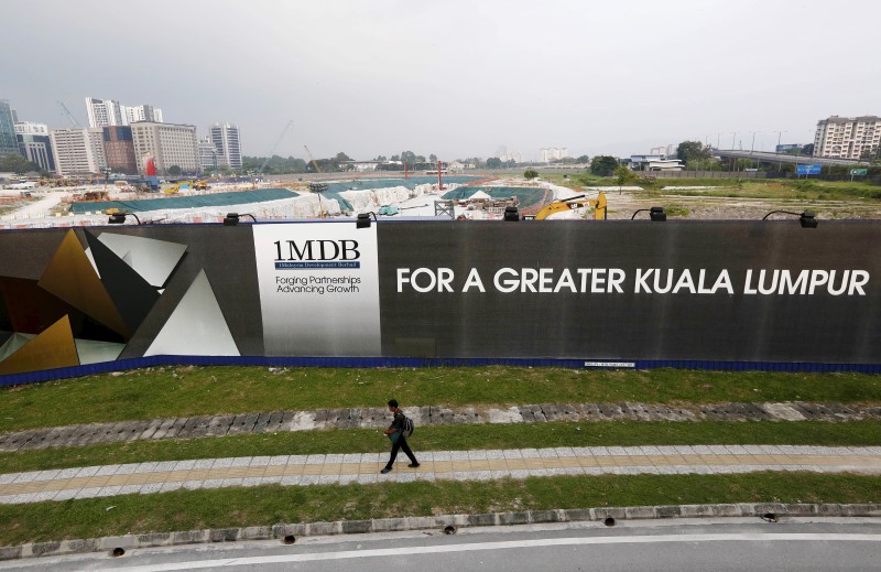 © Reuters. File photo of a man walking past a 1 Malaysia Development Berhad (1MDB) billboard at the funds flagship Tun Razak Exchange development in Kuala Lumpur