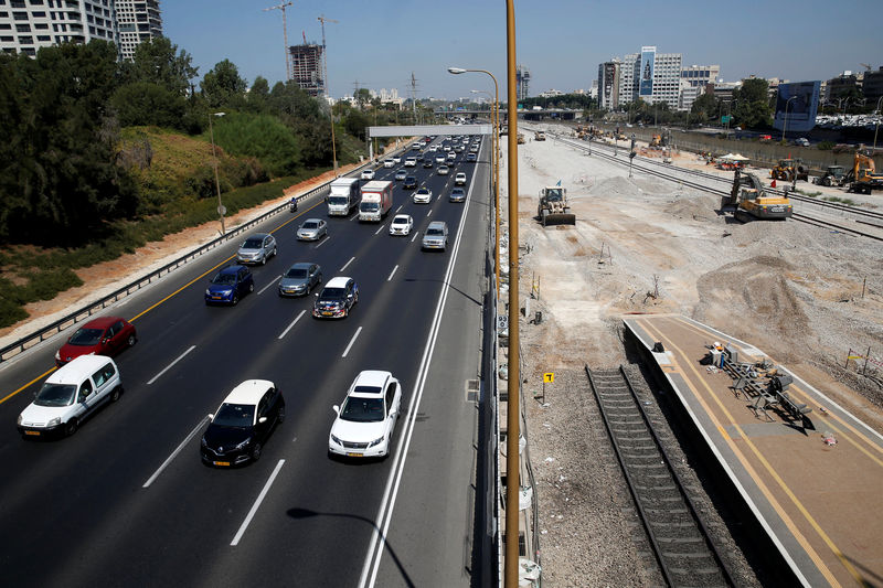 © Reuters. Construction vehicles work at a train station as cars drive on a nearby highway in Tel Aviv, Israel