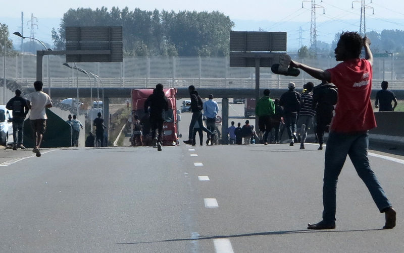 © Reuters. Dozens of migrants gather near lorries which are heading towards the ferry terminal in Calais