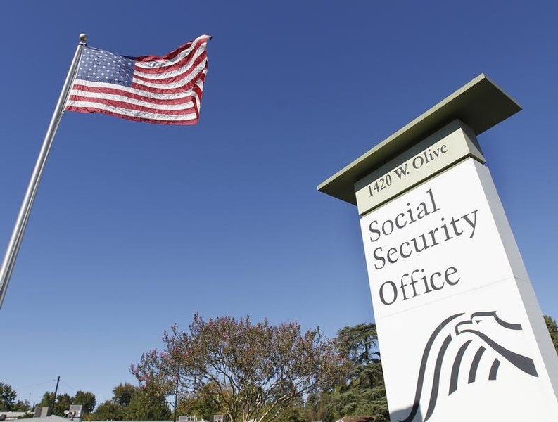 © Reuters. An American flag flutters in the wind next to signage for a U.S. Social Security Administration office in Burbank