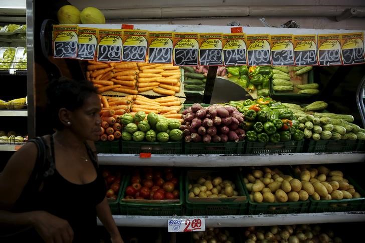 © Reuters. A woman passes by food displayed at a market in Rio de Janeiro