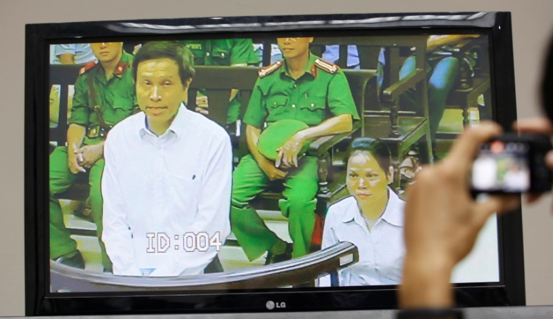 © Reuters. A journalist takes a photo of a live screen from the courtroom showing Vietnamese prominent blogger Anh Ba Sam whose real name is Nguyen Huu Vinh, and his assistant Nguyen Thi Minh Thuy, during their appeal trial in Hanoi