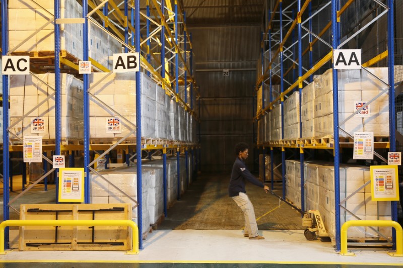 © Reuters. A Department for International Development worker moves boxes containing kitchen sets at a UK aid Disaster Response Center at Kemble Airport, southern England