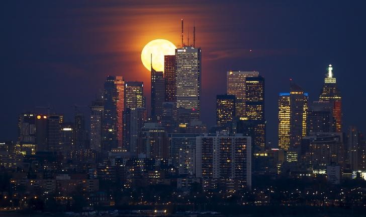 © Reuters. The moon rises behind the skyline and financial district in Toronto