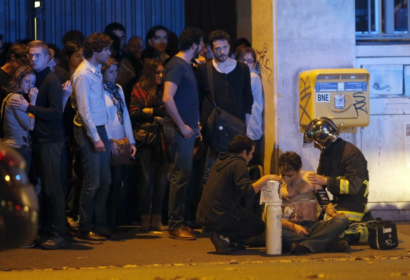 © Reuters. A member of the French fire brigade aids an injured individual near the Bataclan concert hall following fatal shootings in Paris