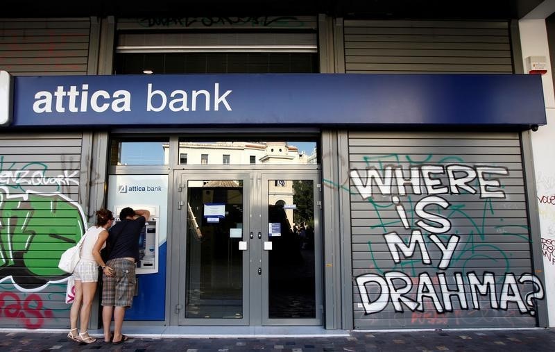 © Reuters. A couple makes a transaction at an ATM outside an Attica bank branch in Athens