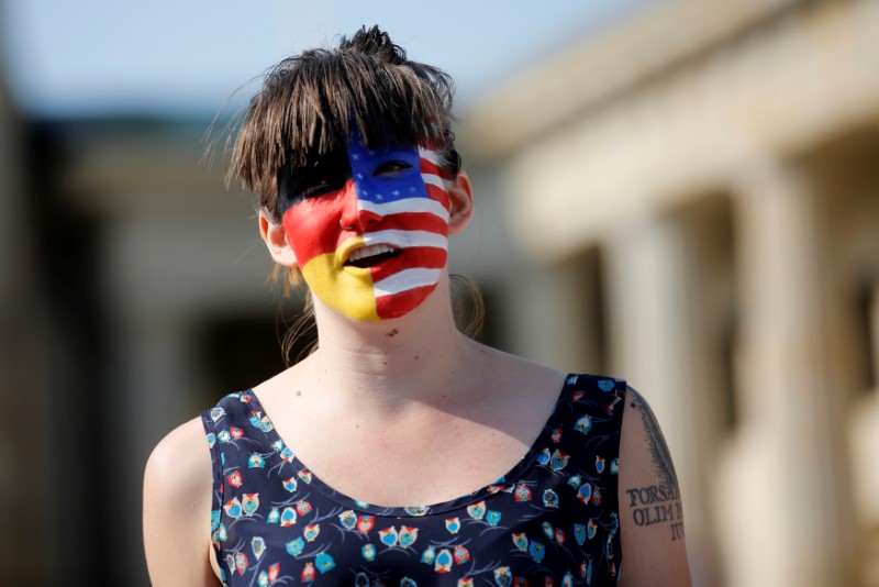 © Reuters. A campaigner with a American and German flag painted on her face stands in front of the Brandenburg Gate to urge Americans living abroad to register and vote in Berlin