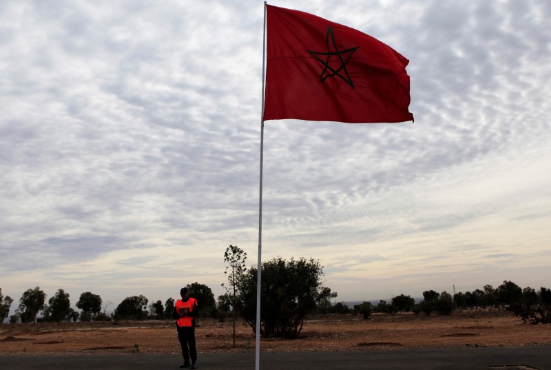 © Reuters. A police officer stands near a Moroccan national flag near the main stadium during preparations for the FIFA Club World Cup in Agadir