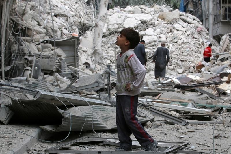 © Reuters. A boy inspects a damaged site after airstrikes on the rebel held Tariq al-Bab neighbourhood of Aleppo