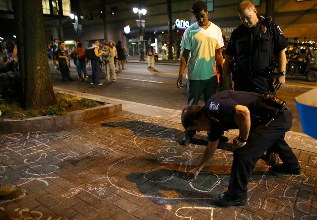 © Reuters. Charlotte police officer Campagna writes a peace sign with chalk on the sidewalk as demonstrators conclude a peaceful night of marching in Charlotte