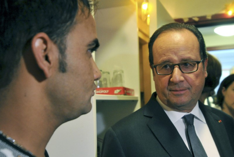 © Reuters. French President Francois Hollande listens to an Afghan migrant at a shelter and orientation centre in Tours