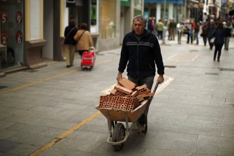 © Reuters. File photo of a construction worker pushing a wheelbarrow loaded with bricks in downtown Ronda