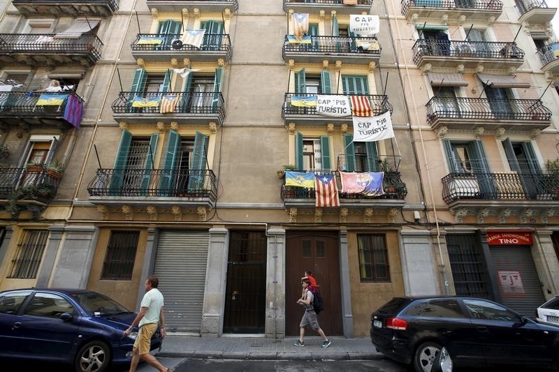 © Reuters. Banners against touristic apartments hang from balconies as people walk past them at Barceloneta neighborhood in Barcelona