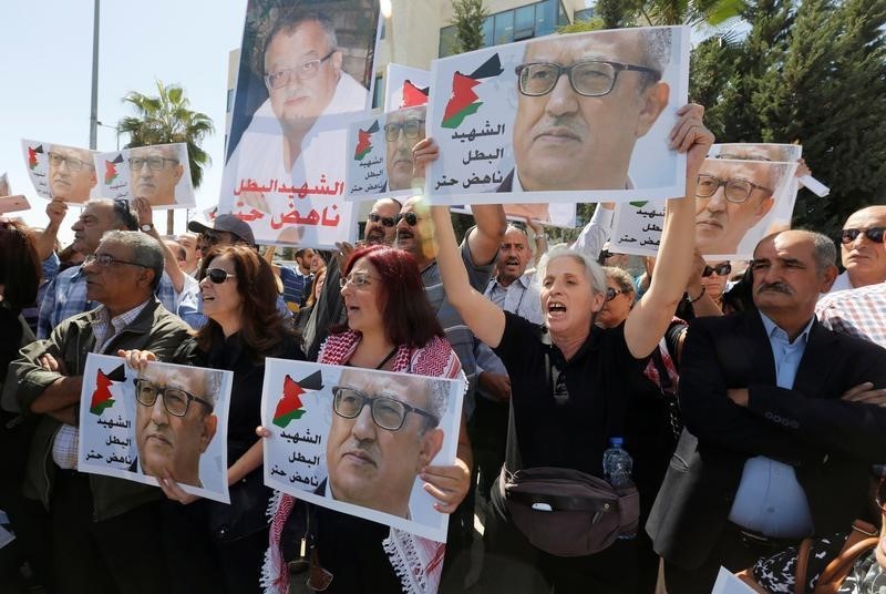 © Reuters. Relatives and activists hold pictures of the Jordanian writer Nahed Hattar, who was shot dead, and shout slogans during a sit-in in front of the prime minister's building in Amman