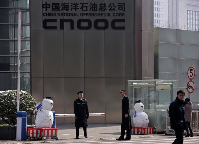© Reuters. Security personnel stand next to snowmen at the entrance of China National Offshore Oil Corp office tower in Beijing
