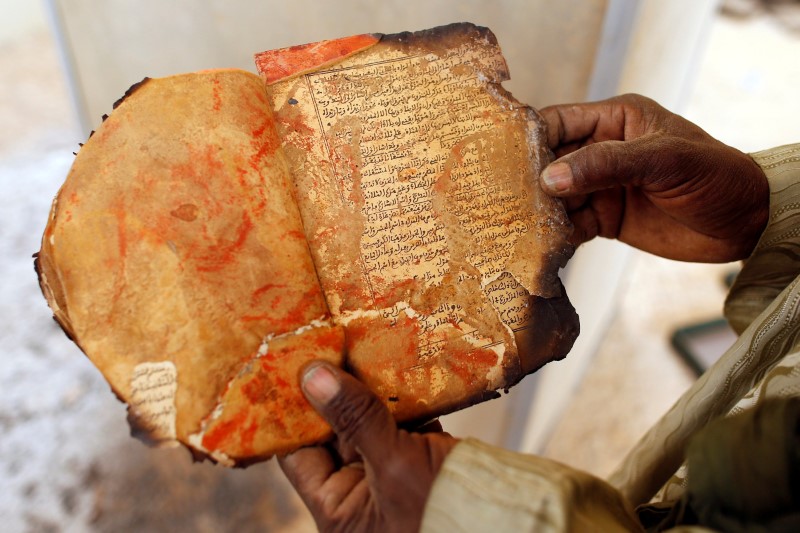 © Reuters. A museum guard displays a burnt ancient manuscript at the Ahmed Baba Institute in Timbuktu
