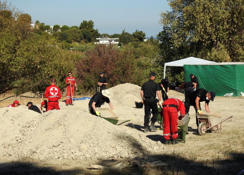 © Reuters. South Yorkshire police officers and members of the Greek rescue service investigate the ground while excavating a site during an investigation for Ben Needham on the island of Kos