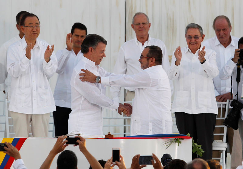 © Reuters. Colombian President Juan Manuel Santos (L) and Marxist rebel leader Timochenko shake hands after signing an accord ending a half-century war that killed a quarter of a million people, in Cartagena